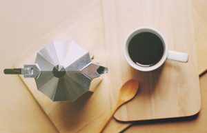 Hot coffee and moka pot with wooden spoon, retro filter effect